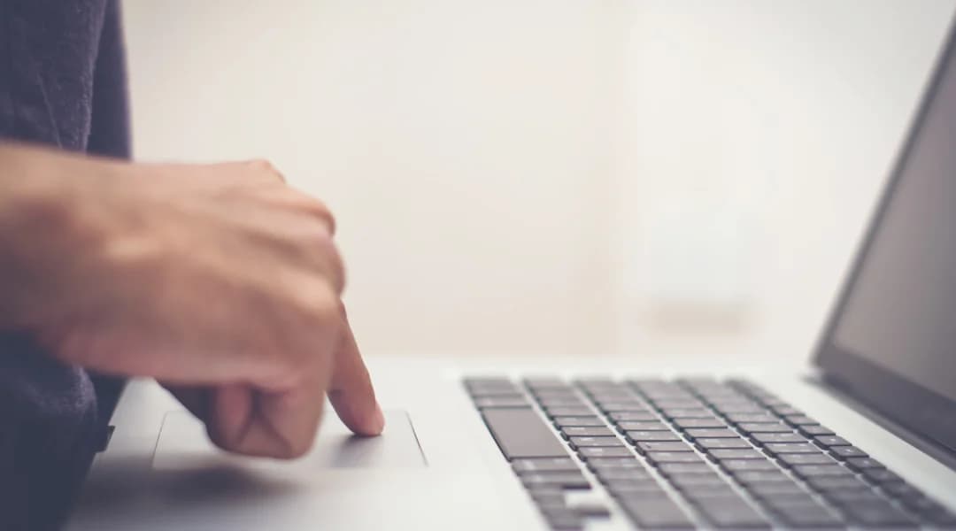 Une personne utilise un ordinateur portable, son doigt posé sur le clavier, effectuant un virement Interac.