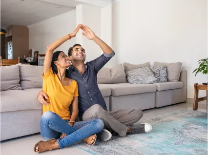A couple sitting on the floor in front of a couch.