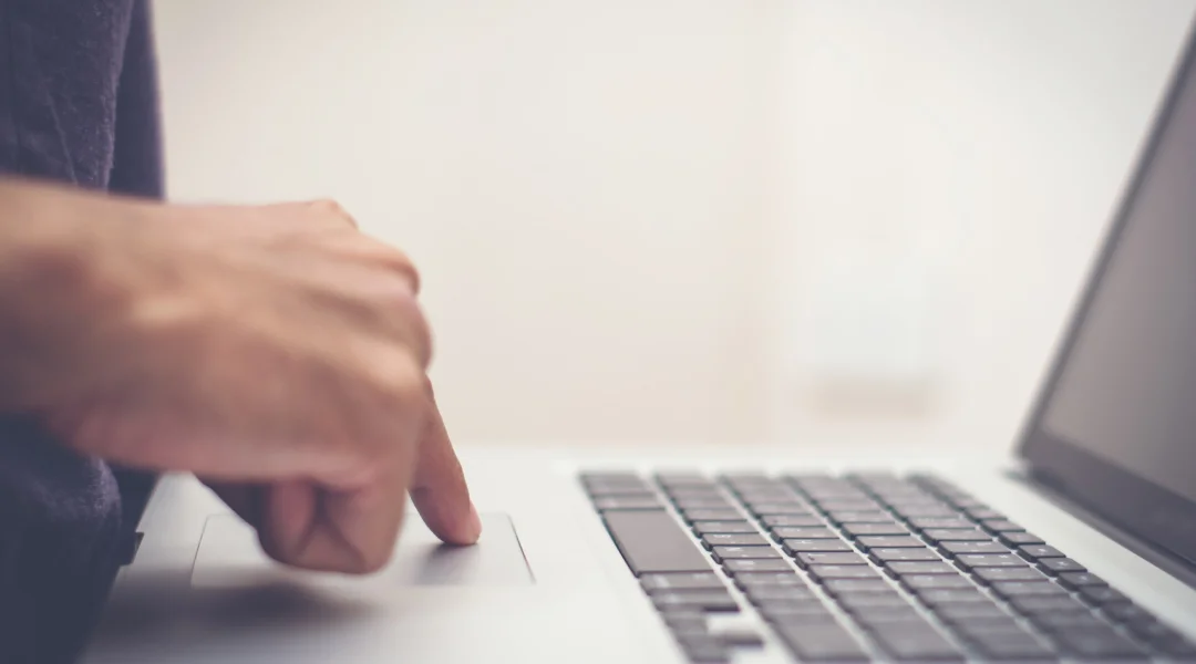A person types on a laptop keyboard, engaged in an interac e-transfer transaction.