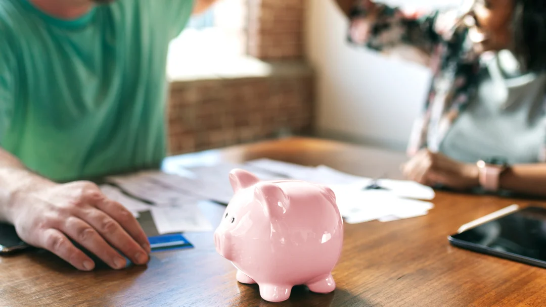 A man and a woman sitting at a table with a piggy bank, discussing instant loans.