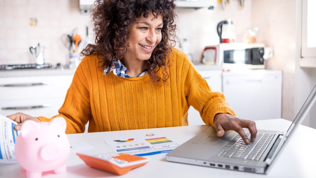 Une femme utilise son ordinateur portable en étant assise à une table, illustrant une ambiance de travail productive.