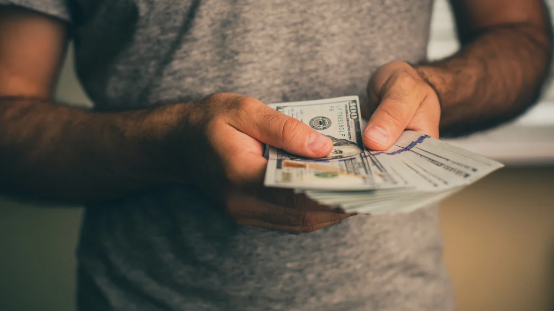 A man holding a stack of cash, symbolizing loan repayment.