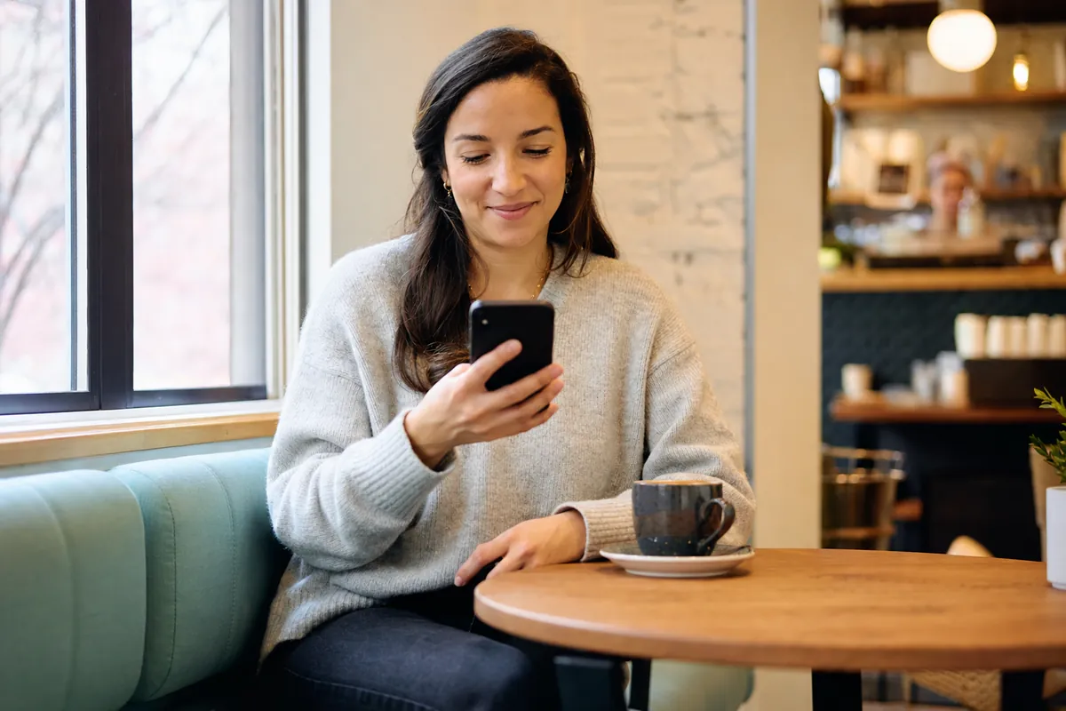 Une jeune femme dans un café consulte son téléphone après une demande de prêt rapide à versements en ligne