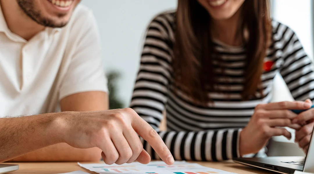 A man and woman are reviewing a laptop screen, discussing options for a small personal loan.