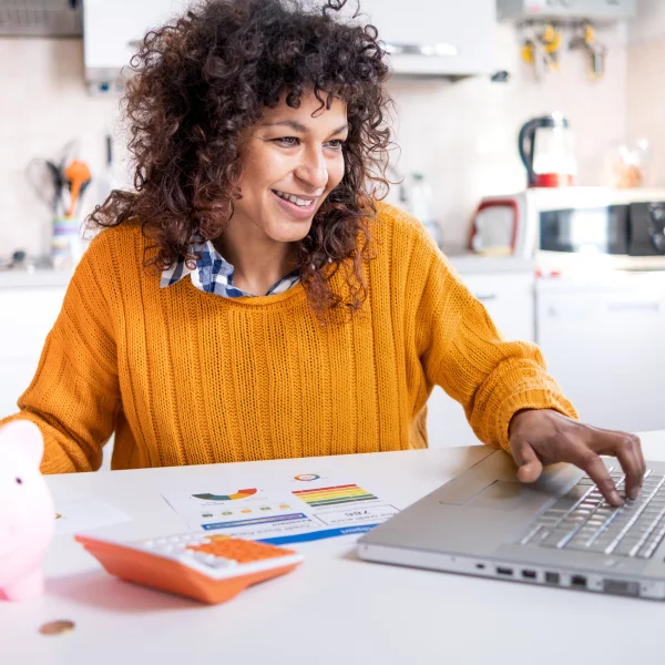 A woman sitting at a table with a laptop, reviewing information about her credit score.