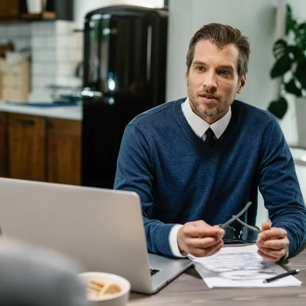 A man sitting at a table with papers and a laptop, working as an independent lender.