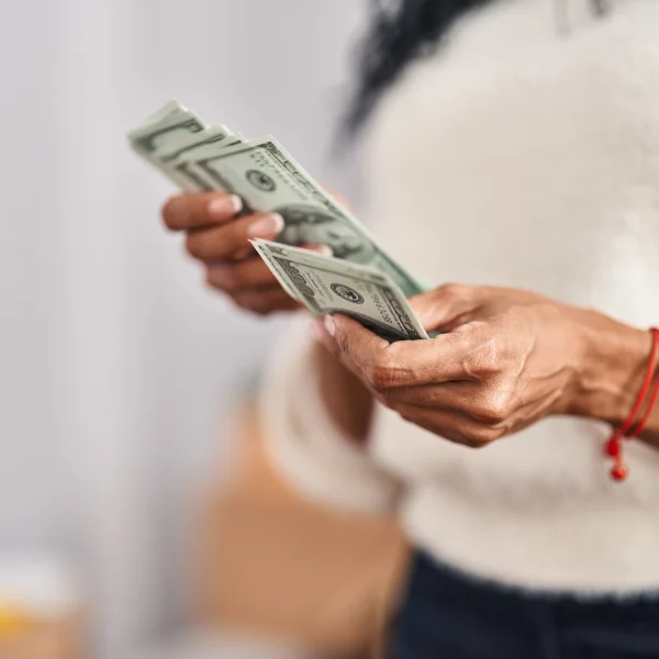 A woman holding cash in her hands, symbolizing loan repayment.